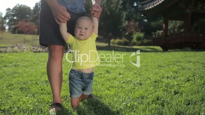 Cute infant taking first steps with father's help