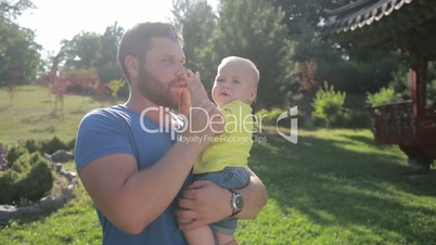 Young hipster father holding little son in park