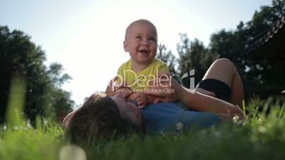 Father and cute toddler son relaxing on park lawn
