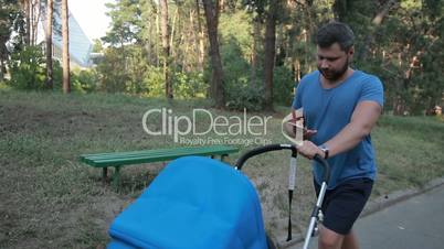 Hipster father with pram walking in public park