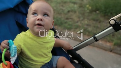 Curious infant boy sitting in pram outdoors