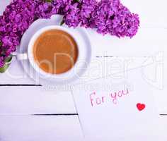 Cup of black coffee and a saucer and white paper envelope