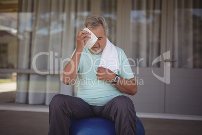 Senior man wiping sweat off his face with towel