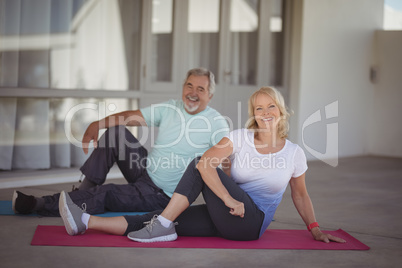 Smiling senior couple performing stretching exercise