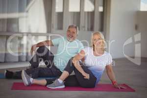 Smiling senior couple performing stretching exercise