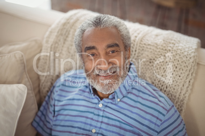 Smiling senior man sitting on sofa in living room