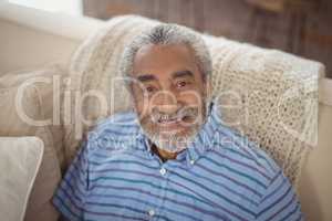 Smiling senior man sitting on sofa in living room