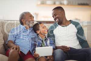 Smiling multi-generation family sitting together on sofa