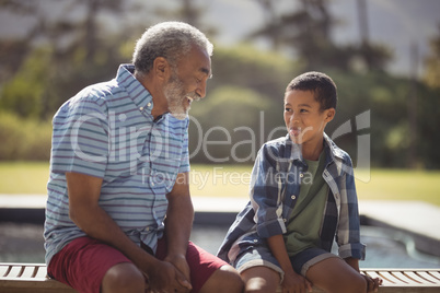 Grandson and grandfather making funny faces near poolside