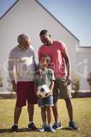 Multi-generation family standing in garden with football