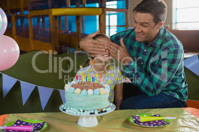 Father closing his daughters eyes during birthday party