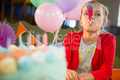 Cute girl blowing party horn during birthday party