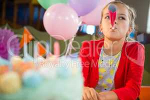 Cute girl blowing party horn during birthday party