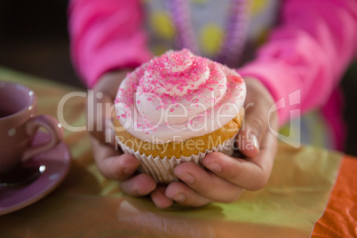 Birthday girl holding a cupcake at home