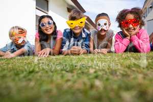 Portrait of children wearing masks lying on field