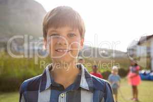 Portrait of smiling boy with friends playing in background