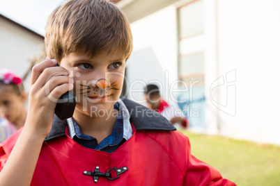 Boy with face paint using walkie talkie while looking away