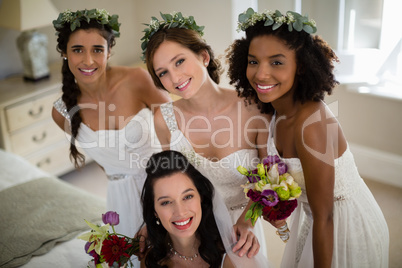 Portrait of smiling bride and bridesmaid in living room