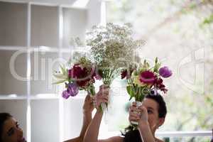 Bride and bridesmaids holding flower bouquet at home