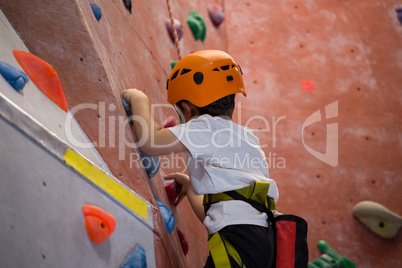 Determined boy practicing rock climbing