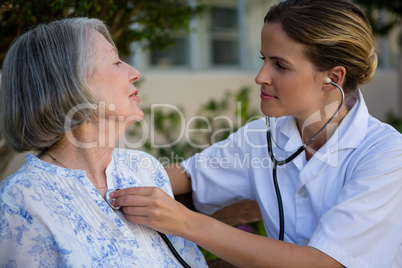 Doctor listening to heart beats of senior woman