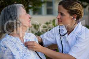 Doctor listening to heart beats of senior woman