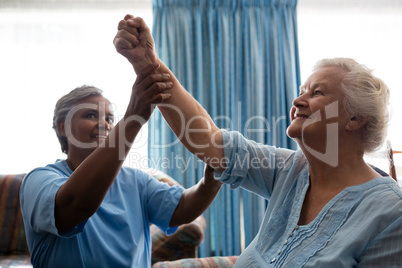 Nurse helping senior woman in flexing muscles