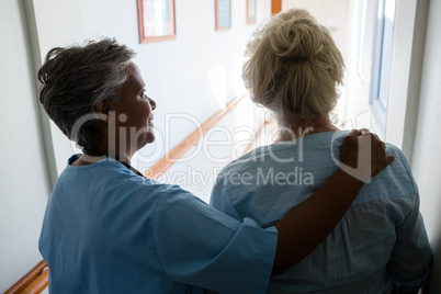 Rear view of nurse senior woman walking in corridor