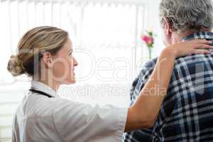 Side view of female doctor consoling senior man