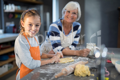 Grandmother and granddaughter posing while flattening dough