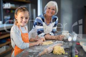 Grandmother and granddaughter posing while flattening dough