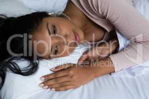 Thoughtful woman relaxing on bed