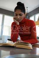 Young woman reading book in kitchen