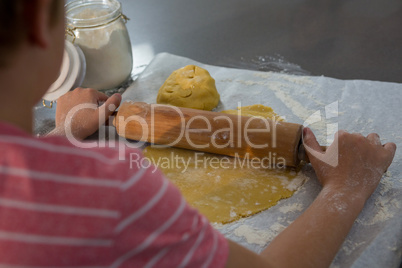 Cropped image of boy rolling dough