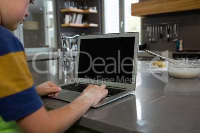 Boy using laptop in kitchen