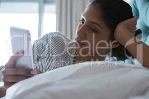 Woman using phone while resting on bed