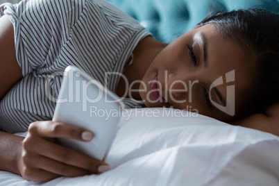 Relaxed woman using phone on bed