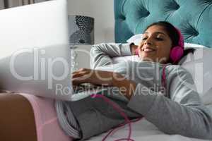 Woman listening to music while resting on bed