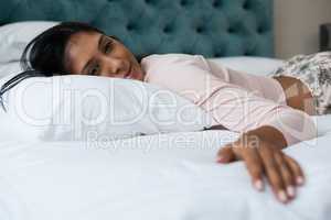 Thoughtful young woman relaxing on bed
