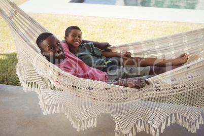 Smiling father and son relaxing on a hammock