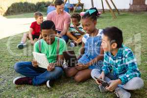 Children using digital tablet with man at park