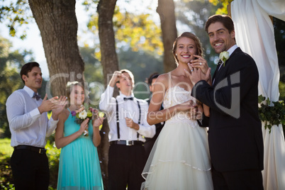 Happy bride and groom showing engagement ring in park