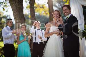 Happy bride and groom showing engagement ring in park