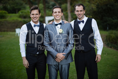 Smiling bridegroom and best man standing in garden