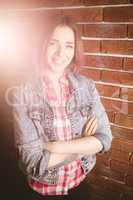 Smiling woman standing with arms crossed against brick wall