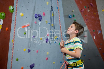 Boy preparing for rope climbing in fitness studio