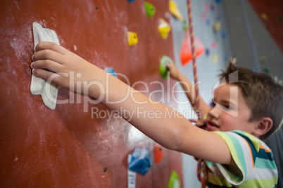 Boy practicing rock climbing in fitness studio