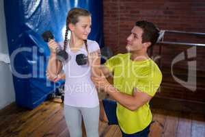 Trainer assisting teenage girl in exercise