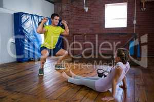 Trainer assisting teenage girl in exercise