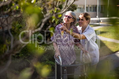Doctor talking to senior woman while assisting her in walking